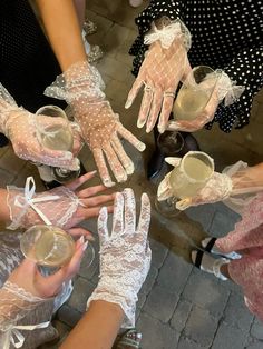 several people wearing white gloves and holding wine glasses in their hands with lace on them