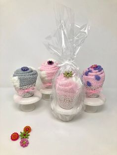 three knitted cupcakes sitting on top of each other next to a plastic bag