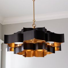 a chandelier hanging from the ceiling with black and gold ribbons on it's sides