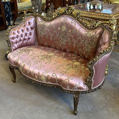 a pink couch sitting on top of a floor next to a table