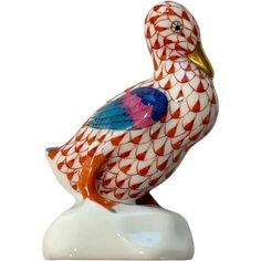 a colorful bird figurine sitting on top of a white base with red and blue patterns