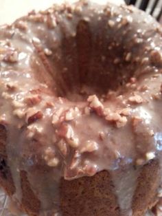 a bundt cake with frosting and nuts on top sitting on a cooling rack