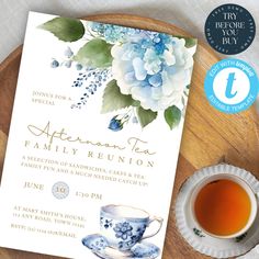 a blue and white floral tea party is set on a wooden tray next to a cup of tea