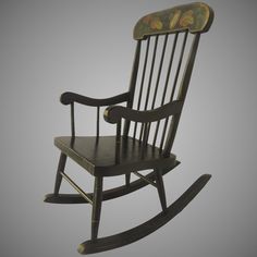 a wooden rocking chair with a butterfly painted on the back and seat, against a gray background