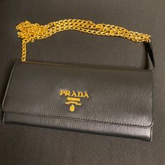 This New Fabulous Sleek Accessory Comes With Luxurious Saffiano Leather. It Has 2 Main Pockets, One Zip Pocket 6 Card Slots, And It Is Very Easy To Maintain And Clean. Authentic, Never Used, Detachable Chain, Dust Bag Included. Certificate Of Authenticity Included. Luxury Gold Wallet On Chain For Business, Designer Gold Wallet With Chain Strap, Elegant Gold Wallet On Chain For Business, Luxury Black Wallet On Chain For Party, Formal Black Wallet On Chain, Evening Wallets With Chain Detail, Black Evening Wallet With Chain Strap, Black Evening Wallets With Chain Strap, Designer Wallets With Chain Strap For Formal Occasions