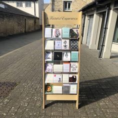 a wooden display case filled with lots of cards and magnets on the side of a street