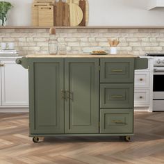 a green kitchen island with wooden top in front of a brick wall and white cabinets