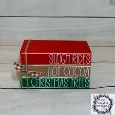 three books sitting on top of each other with ribbons tied around them and the words sleigh rides, hot cocoa, christmas trees