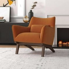 an orange chair sitting in front of a fire place next to a white rug on the floor