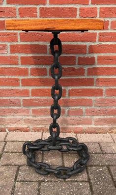 a bench with chains attached to it against a brick wall