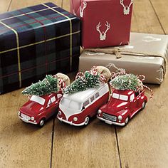 two red cars with christmas trees on the roof are sitting next to presents and wrapped gifts