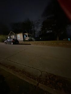 a car parked in front of a house on the side of the road at night