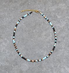 Cheerful seed bead necklace with irregular 4 mm beads. The length can be adjusted with 2 inches (5 cm). The colors of the beads are matte light blue and black. The bronze beads in between give the necklace an elegant sparkle.  A perfect necklace to cheer up a plain outfit. Also eye catching to wear a few of them together in different lengths. The necklace is finished with a Designer Quality brass clasp and findings Here you find my shop: https://MacchiatoSoul.etsy.com * Macchiato Soul offers uni Turquoise Beaded Necklaces With Black Beads For Festival, Blue And Black Beads Bohemian Necklace, Blue Necklaces With Black Beads For Festival, Blue Necklace With Black Beads For Festival, Bohemian Blue And Black Beaded Necklaces, Artisan Blue Beaded Necklace With Tiny Beads, Artisan Blue Heishi Beaded Necklaces, Artisan Blue Heishi Beads Necklace, Southwestern Blue Beaded Necklace With Tiny Beads