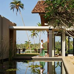 a man standing on the edge of a pool next to a house with palm trees