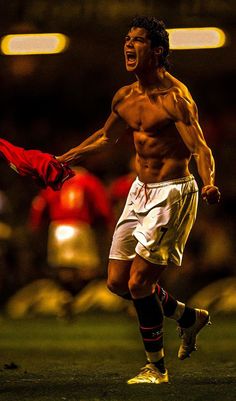 a shirtless male soccer player running on the field with his arms out and mouth wide open