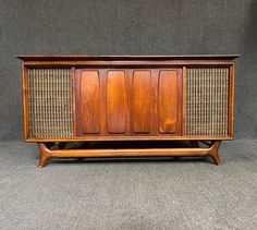 an old fashioned wooden cabinet with wicker panels on the front and sides, against a gray background