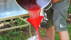 a man pours red liquid into a blender in front of an outdoor table