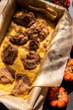 a casserole dish with meatballs and cheese on top, surrounded by mini pumpkins