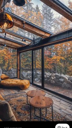 a living room filled with lots of furniture next to a large glass wall covered in trees