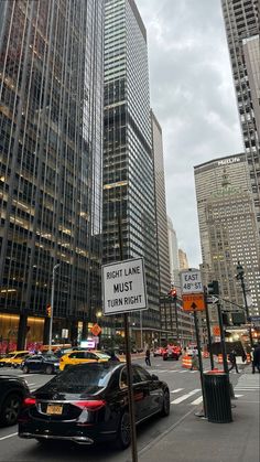 a street scene with cars and tall buildings in the background at night, there is a sign that says might we just turn right?