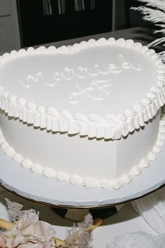 a heart shaped cake sitting on top of a white plate next to flowers and feathers