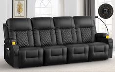 a black leather couch with two reclining seats in front of a wall mounted clock