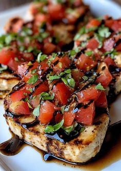 grilled chicken topped with tomatoes and basil on a white plate