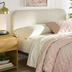 a bed sitting next to a nightstand with a lamp on it's headboard