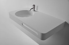 a white bathroom sink sitting on top of a counter next to a wall mounted faucet