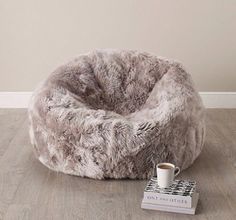 a bean bag chair sitting on top of a hard wood floor next to a book