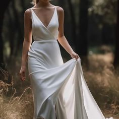 a woman in a white dress is walking through the woods