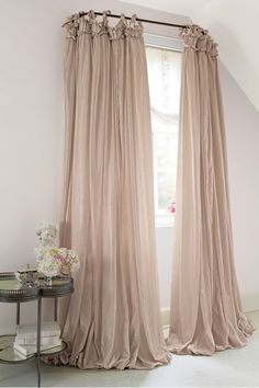 the curtains are hanging in front of a window with white walls and windowsills