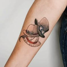 a woman's arm with a hat and eyeglasses tattoo on the wrist