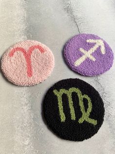 three crocheted coasters with the zodiac signs on them