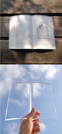 an open book sitting on top of a wooden table next to a person's hand