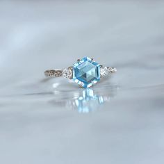 an aqua and white diamond ring with three diamonds around it, on a shiny surface