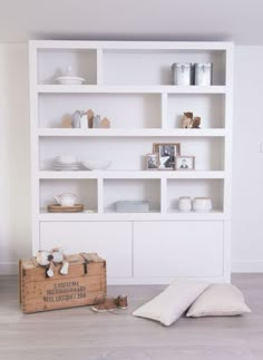 a white bookcase filled with lots of books on top of a hard wood floor