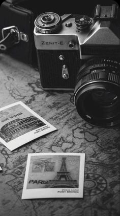 an old camera sitting on top of a table next to some pictures and a pen