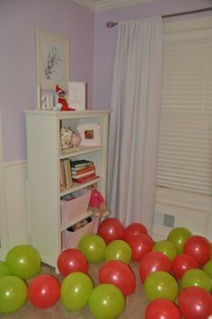 there are many red and green balloons on the floor in front of a bookcase