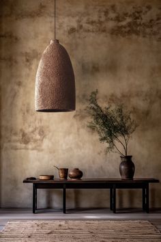 a table with two bowls on it and a vase hanging from the ceiling over it