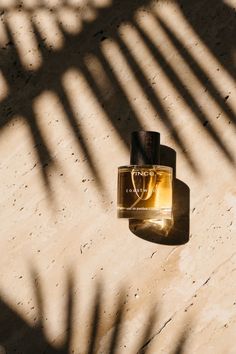 a bottle of perfume sitting on top of a counter next to a shadow cast wall