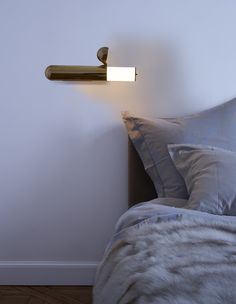 a light that is on the side of a wall next to a bed with pillows