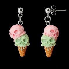 two ice cream cones with skulls on them are hanging from silver ear hooks, one is green and the other is pink