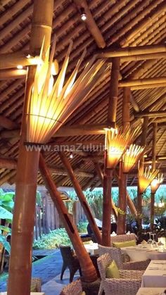 an outdoor dining area with wicker chairs and tables under a thatched roof at night