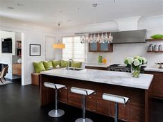 a kitchen with an island and bar stools next to the stove top oven in it