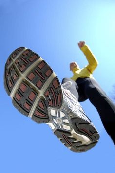 a person jumping up into the air with their feet in the air while wearing running shoes