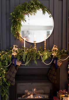 a fireplace decorated for christmas with stockings and candles