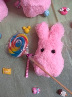 a pink stuffed bunny with candy and lollipops on the ground next to it