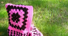 a pair of pink and black crocheted boots sitting in the grass