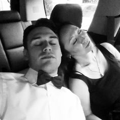 a man and woman sleeping in the back seat of a car with their eyes closed